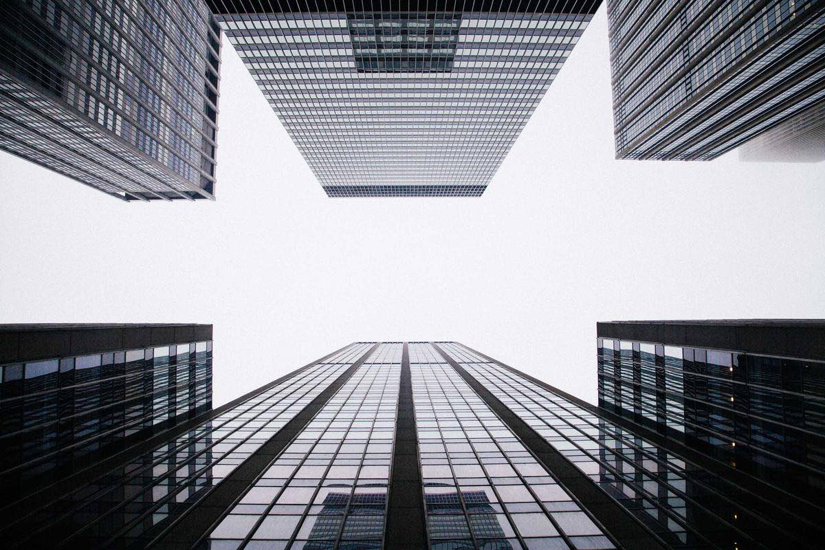 Glass towers seen from below converging on the sky